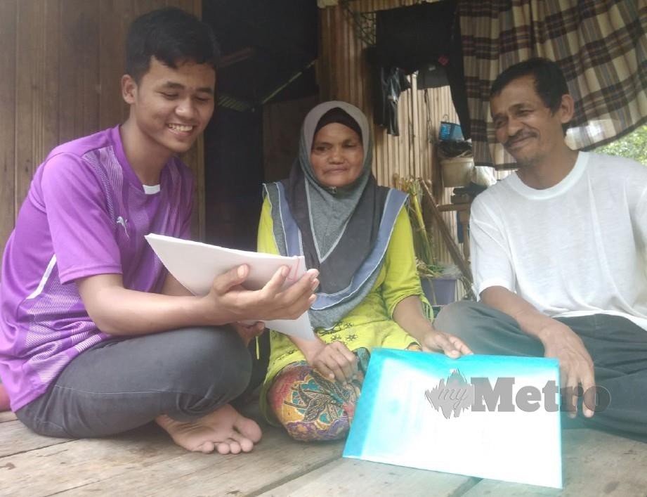 MUHAMMAD Iskhandar menunjukkan surat tawaran untuk melanjutkan pelajaran kepada ibu bapanya. FOTO Syaherah Mustafa